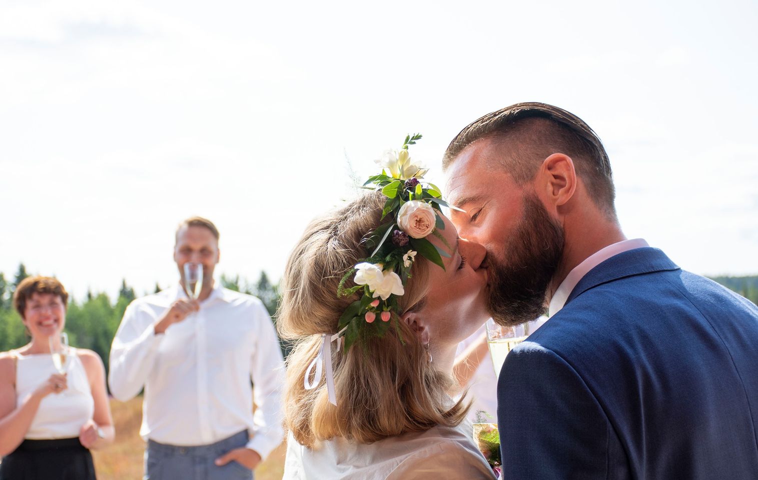 Wedding couple kissing with onlookers - by Essi Photography