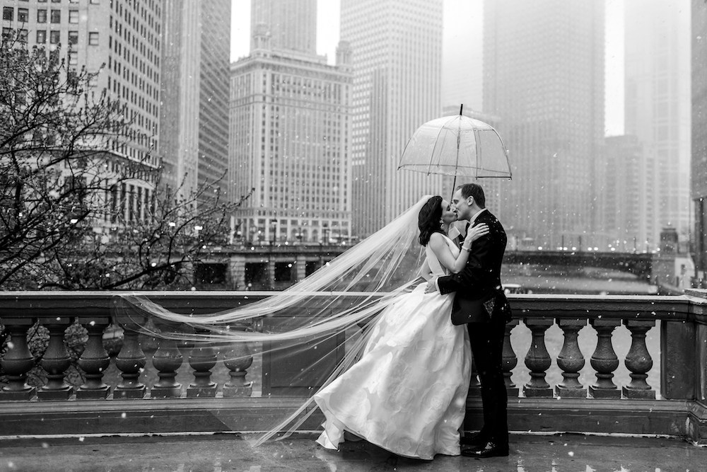 Jennifer Boris Photography preview image - bride and groom kiss under umbrella with Chicago backdrop and snow